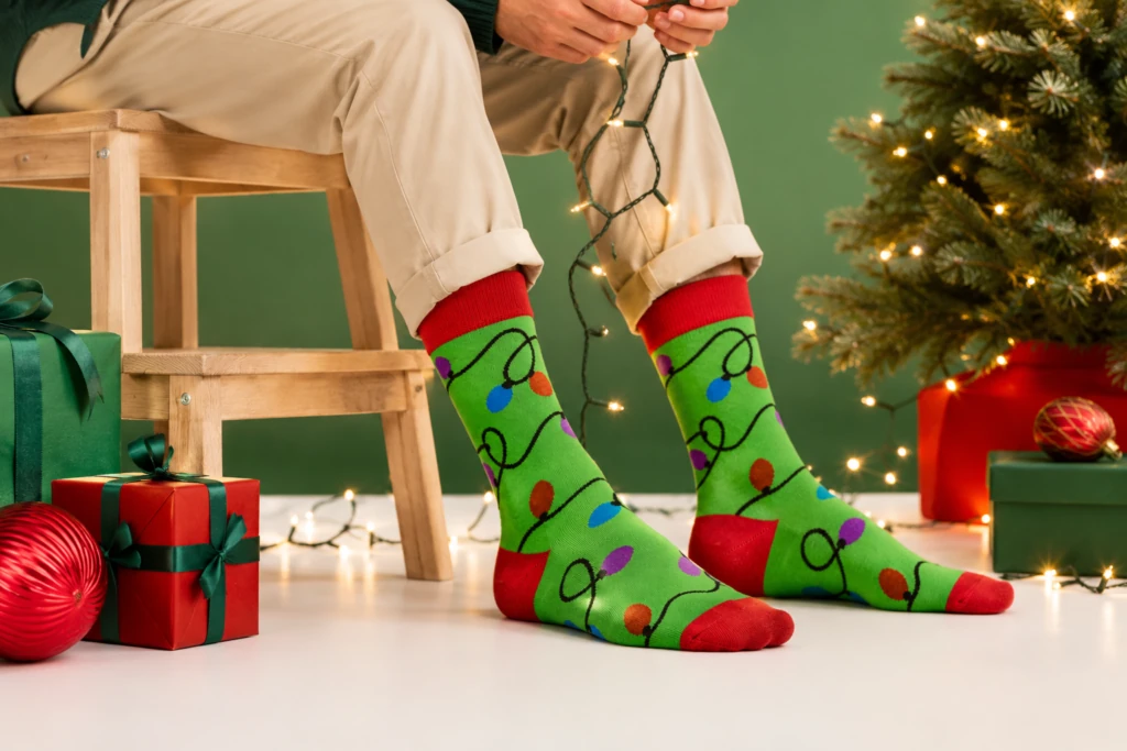 Green socks with Christmas lights beside a decorated tree